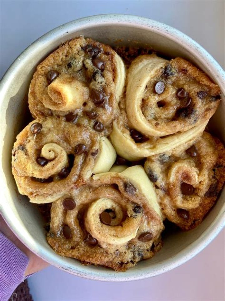 Cinnamon roll cookie dough in a white bowl with a rubber spatula.