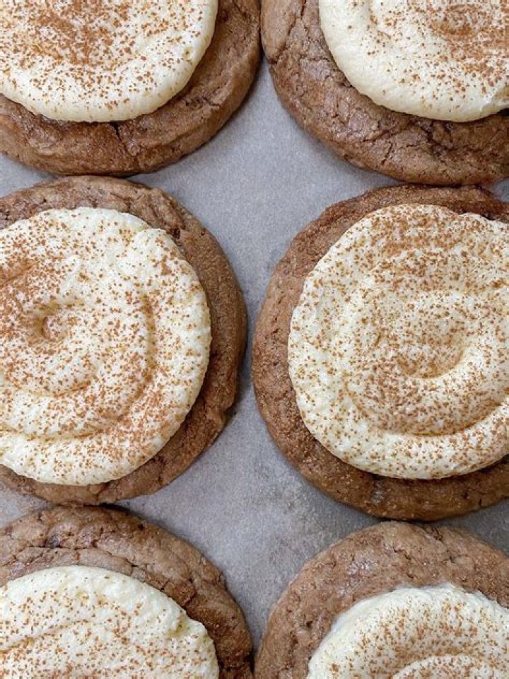 Cinnamon roll cookies on a baking sheet with a blue round cookie cutter.